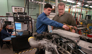 Shaver, left, an assistant professor of mechanical engineering at Purdue, and graduate student David Snyder discuss how to modify a commercial diesel engine with a new technology.