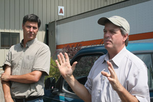 Walker, left, and Charlie Niebling, general manager of New England Wood Pellet, talk to tour participants about the wood pellet industry and the challenges they face. 