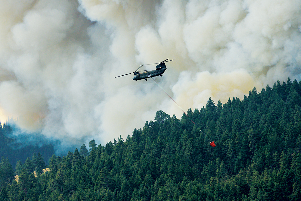 COMBATING NATURE:  An Oregon Army National Guard CH-47 Chinook helicopter flies past the Government Flats Complex fires after dumping a â€œBambiâ€� bucket of water on the fire near The Dalles, Ore., in August. ORARNG believes using biomass pellets an