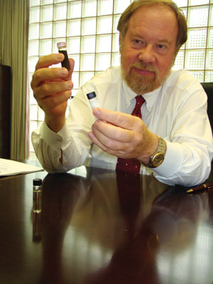 Syntroleum CEO Jack Holmes holds up vials of black rendered poultry fat and white Fischer-Tropsch wax. Both can be refined into clear synthetic diesel or jet fuel.