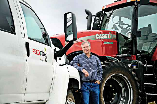 Roskam stands next to a Feedstox vehicle and a Case IH 275 Magnum tractor used to pull a square baler, part of the nonprofitâ€™s fleet of biomass harvesting equipment.